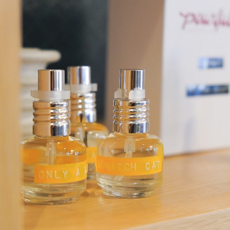 Three small bottles of perfume with yellow labels on a wooden surface.