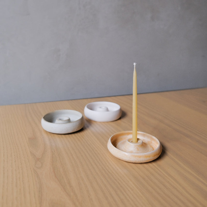 Set of three ceramic candle holders on a wooden surface with a gray background