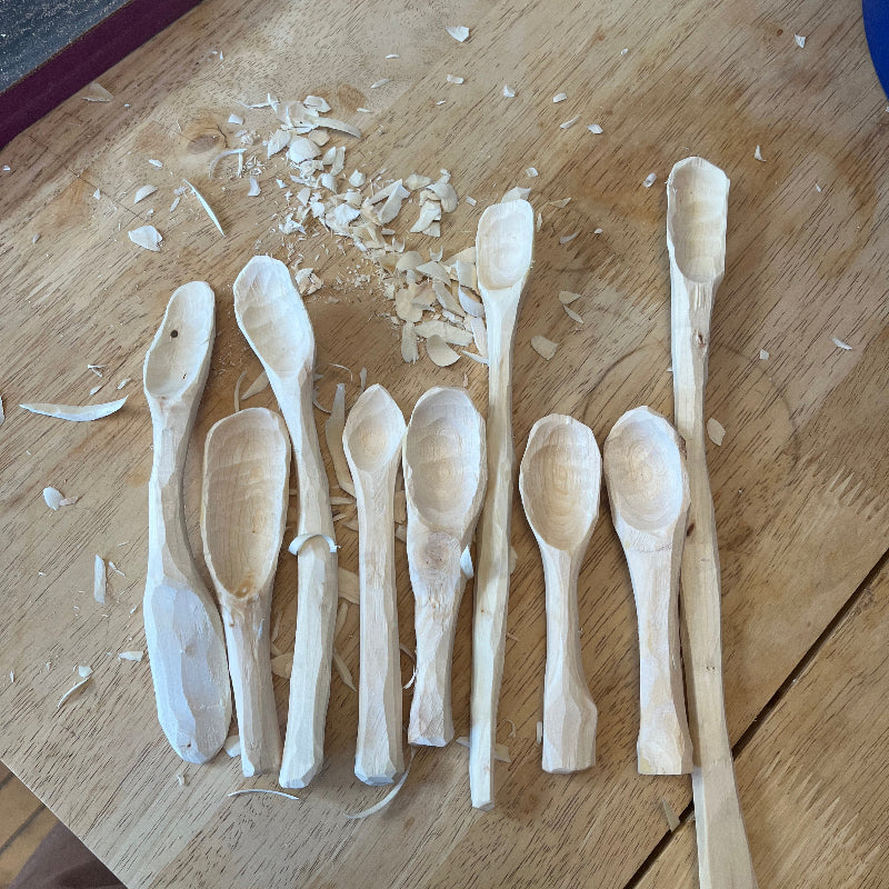 Wooden spoons on a wooden surface with scattered wood shavings.