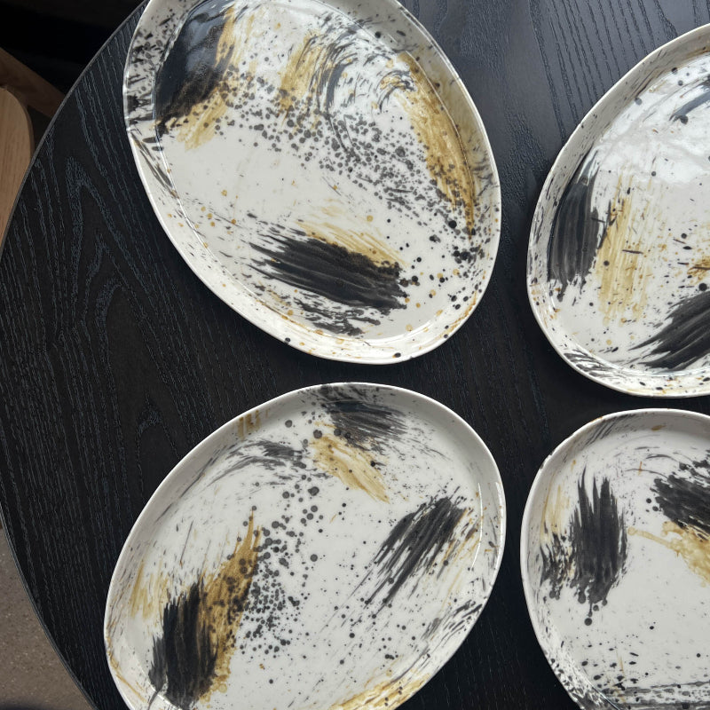 Four porcelain Monsoon Pottery platters with abstract designs on a dark surface