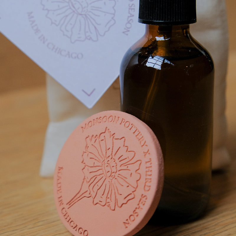 Amber glass bottle with black cap and terracotta diffuser stone on a wooden surface.