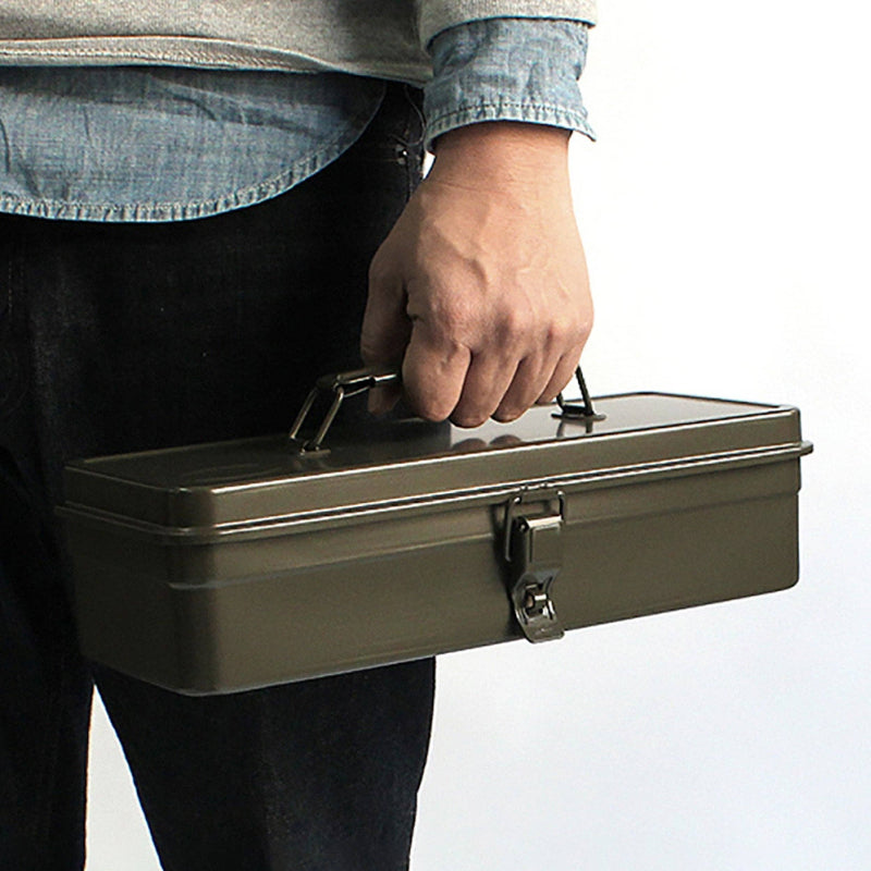 Person holding a green metal toolbox against a white background