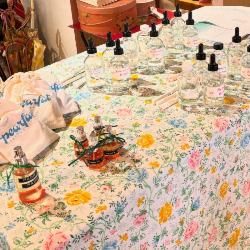 Table with floral tablecloth displaying various bottles and bags.