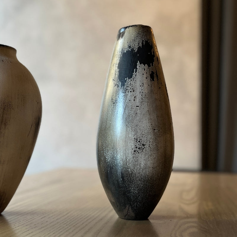 Two wooden vases with textured surfaces on a wooden surface.